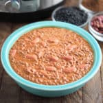 A bowl of lentils and kidney beans (dal makhani), with beans and spices in the background