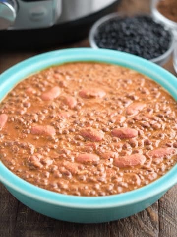 A bowl of lentils and kidney beans (dal makhani), with beans and spices in the background