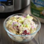 A bowl of ranch potato salad with an Instant Pot and bottle of dressing in the background