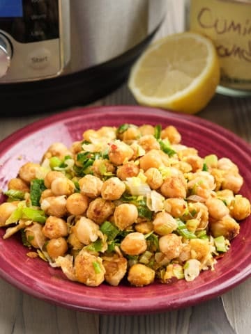 A plate of smashed chickpea and scallion salad, with a lemon, some spices, and an Instant Pot in the background
