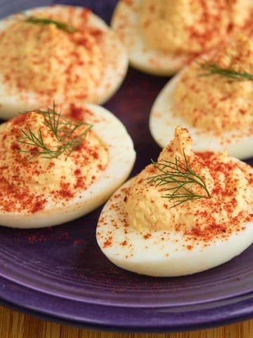 A plate of horseradish deviled eggs sprinkled with paprika and topped with a sprig of dill