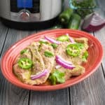 A plate of pork chops with jalapeños and red onions, with an Instant Pot in the background