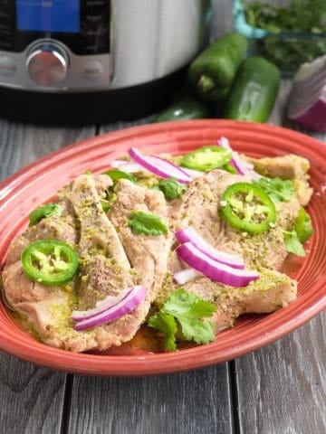 A plate of pork chops with jalapeños and red onions, with an Instant Pot in the background