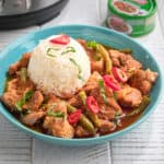 A bowl of prik king pork curry with a scoop of rice, topped with slivered basil and Thai red peppers