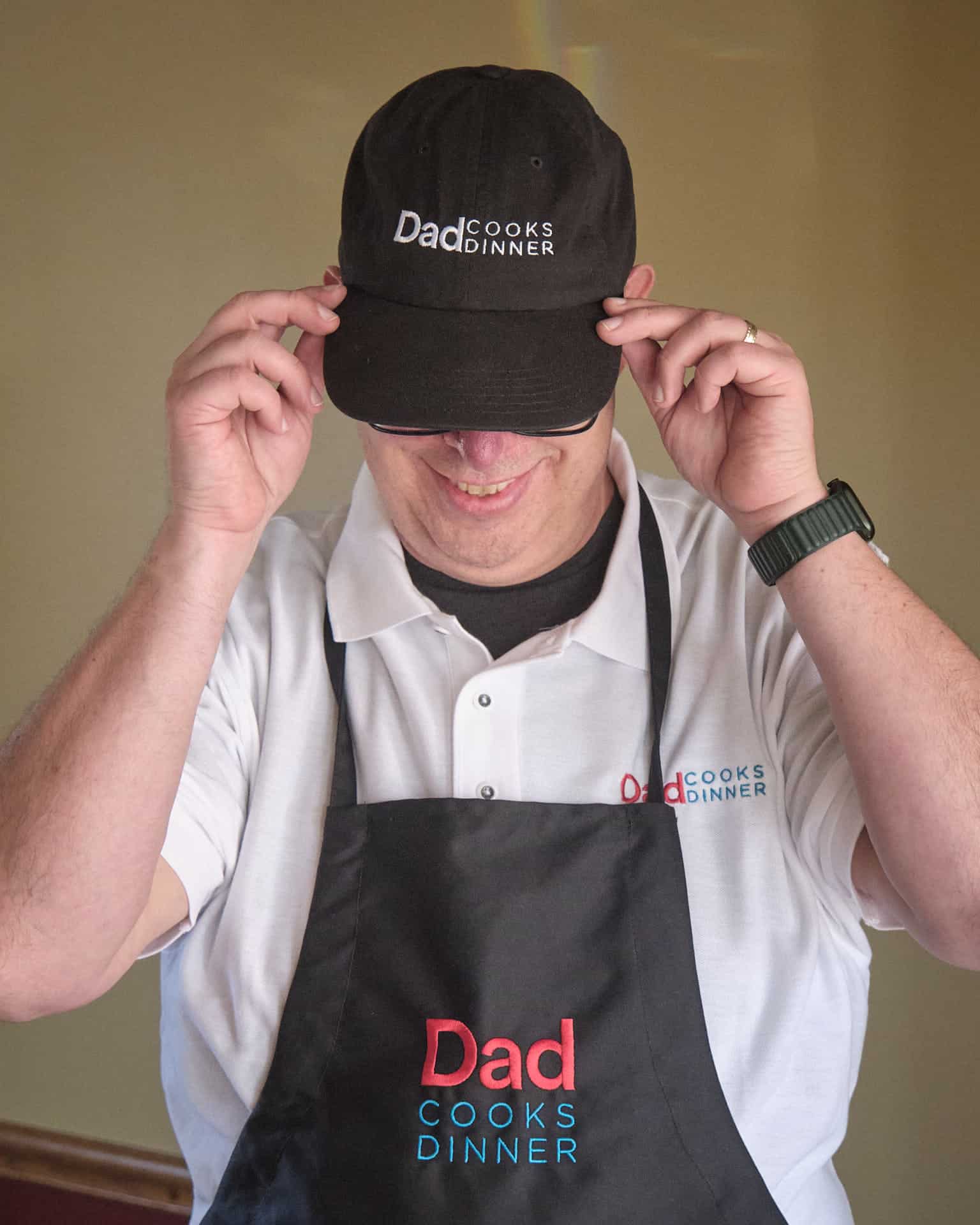 DadCooksDinner wearing a logo hat, polo, and apron