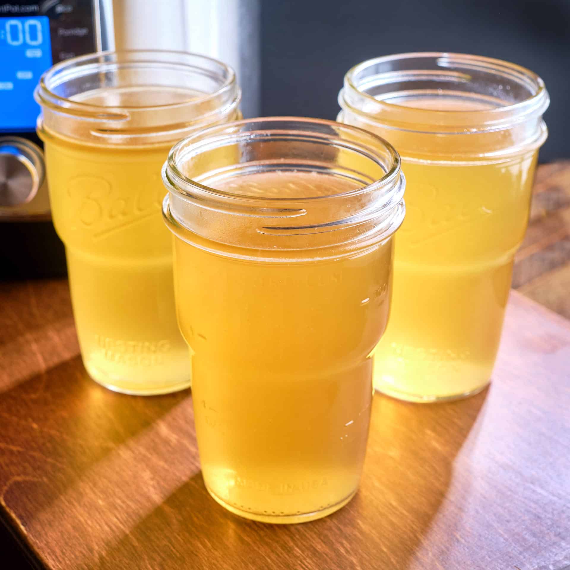 Jars of turkey back broth with an Instant Pot in the background