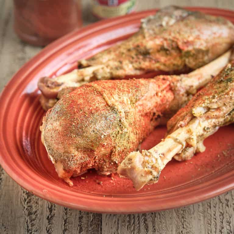 Turkey drumsticks, sprinkled with spices, on a platter