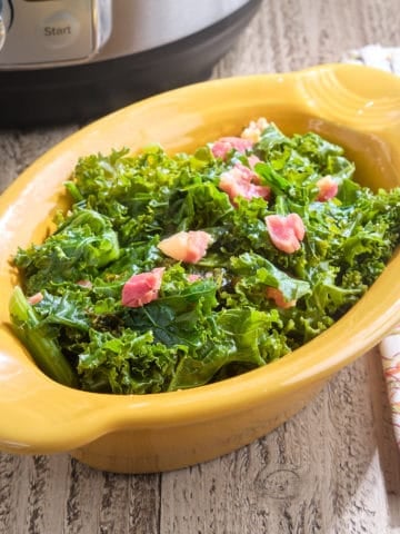 A bowl of cooked kale and pancetta, with a napkin and an Instant Pot in the background