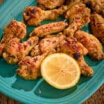 A platter of lemon pepper chicken wings, with a lemon half