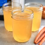 Three jars of ham broth, with carrots, onions, and an Instant Pot in the background.