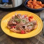 A plate of lamb shoulder chops, sprinkled with parsley, with carrots and tomatoes on the side