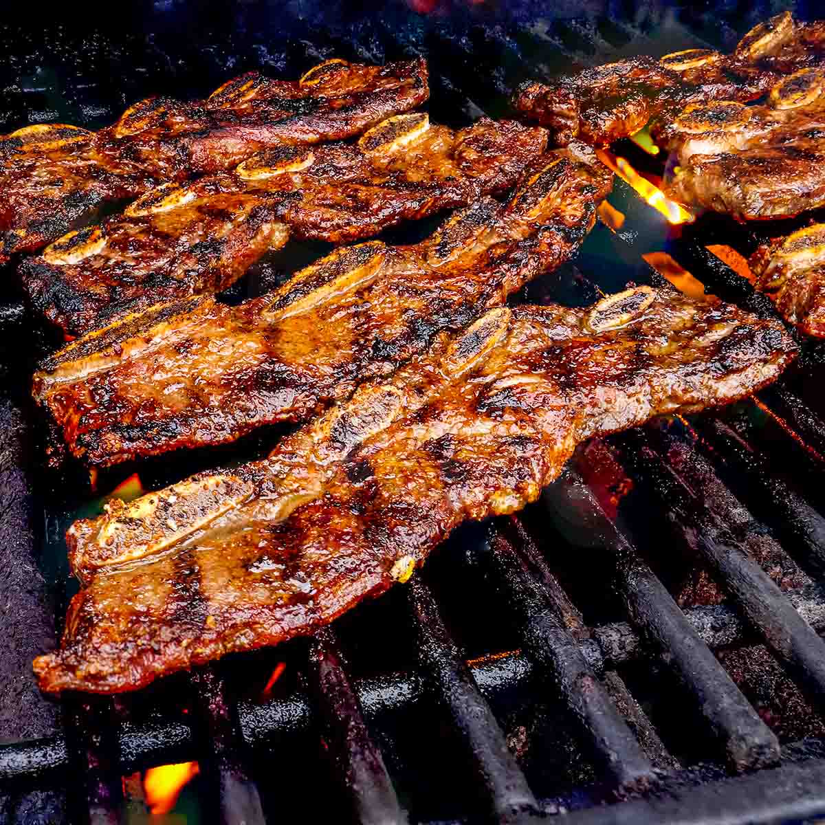 Beef short ribs on the grill, with some flareups in the background