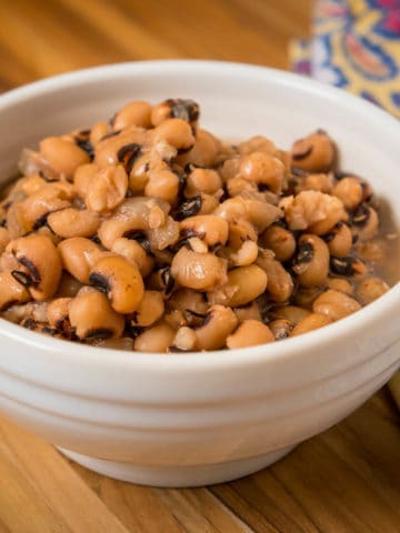 A bowl of cooked black eyed peas on a wooden tabletop