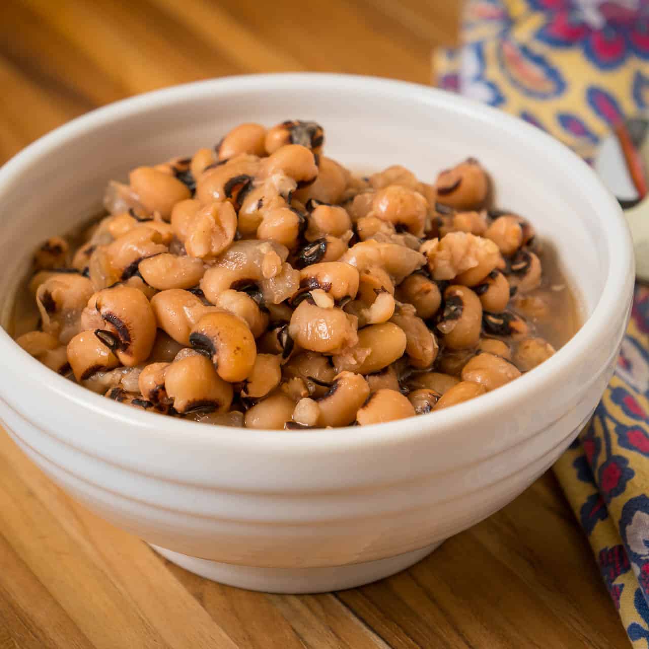 A bowl of cooked black eyed peas on a wooden tabletop