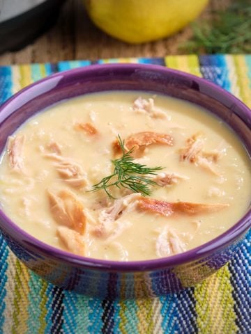 A bowl of rotisserie chicken lemon and rice soup, with a sprig of dill on top