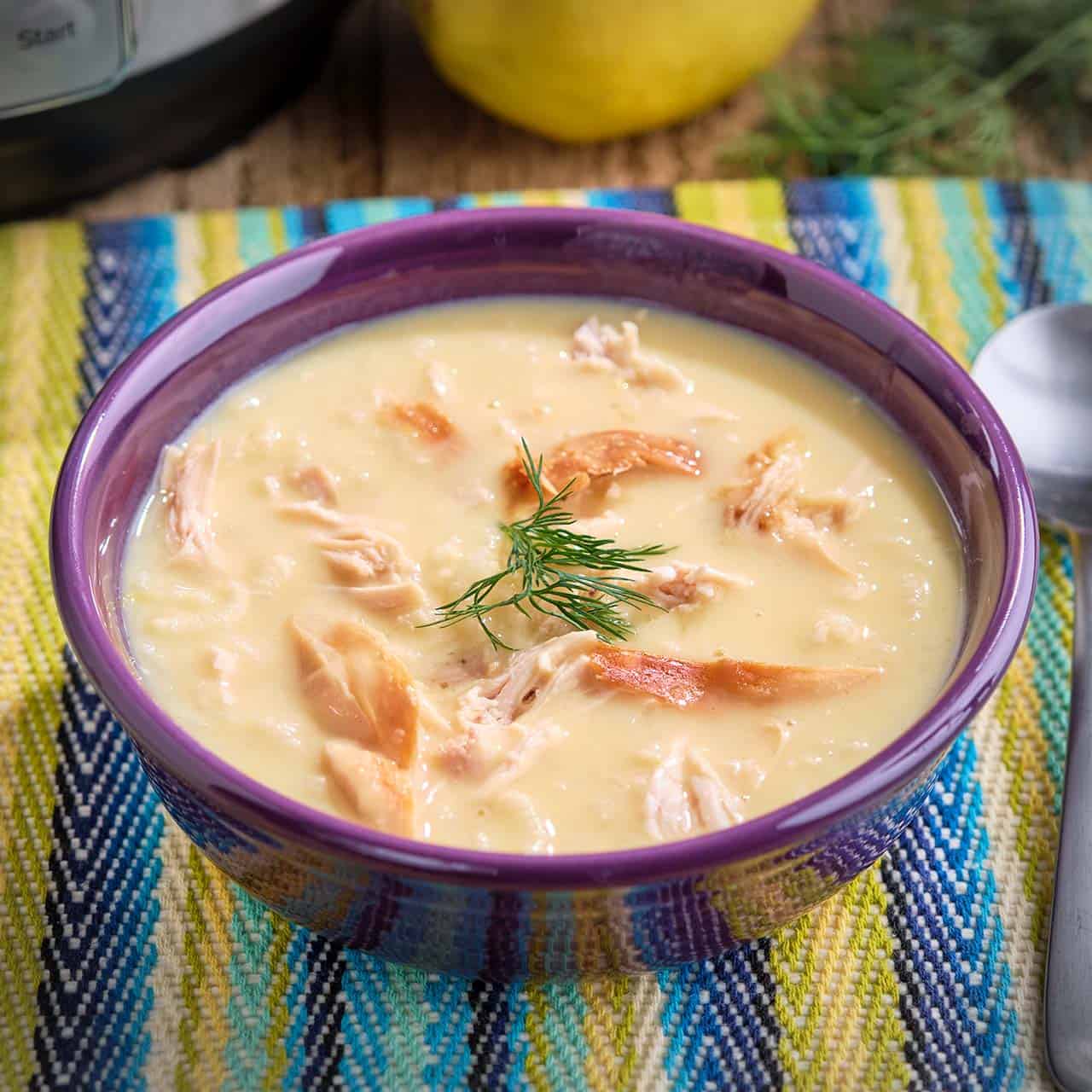 A bowl of rotisserie chicken lemon and rice soup, with a sprig of dill on top