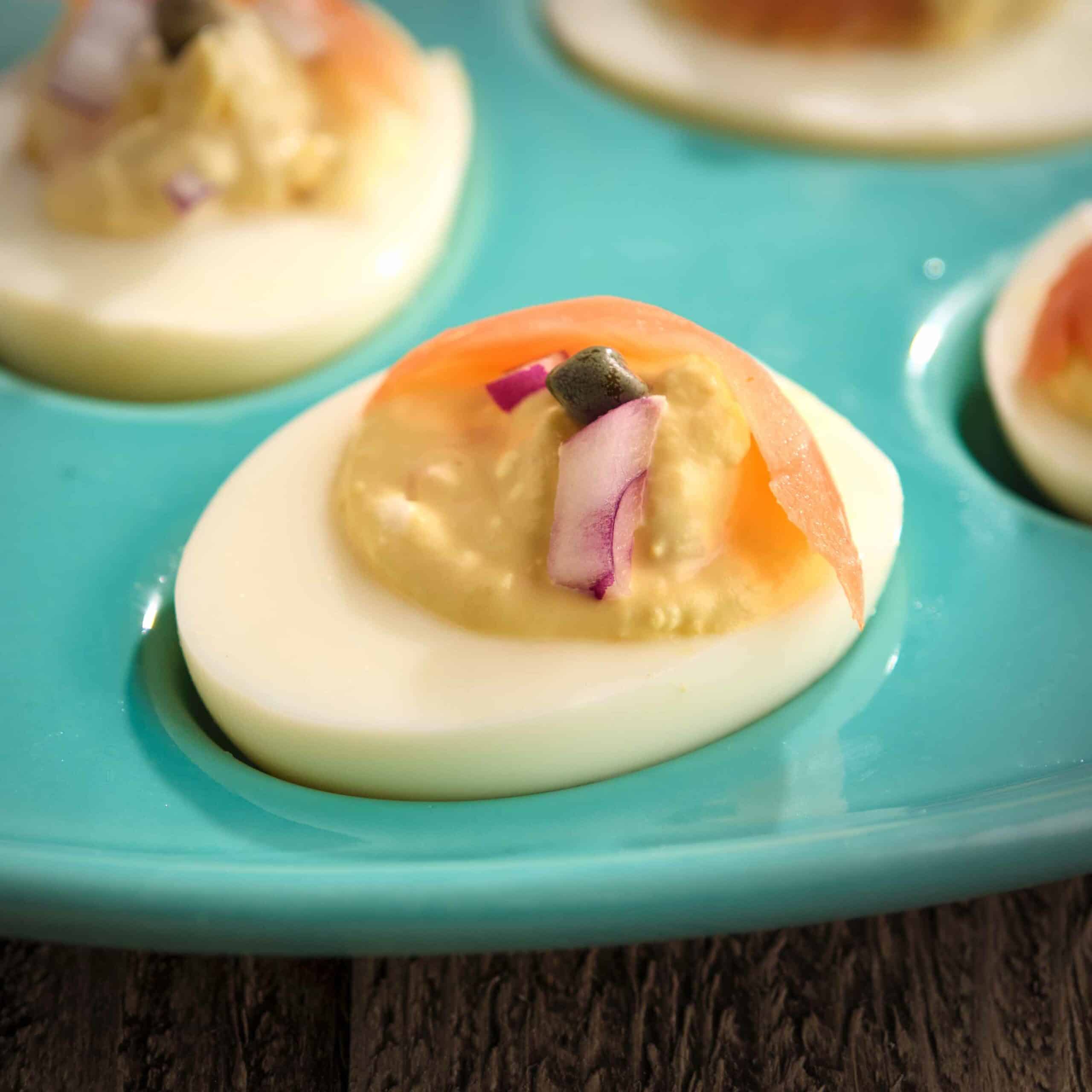 A smoked salmon deviled egg on a teal egg plate