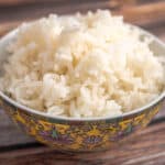 A bowl of white rice on a wood table