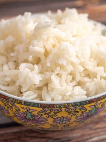 A bowl of white rice on a wood table