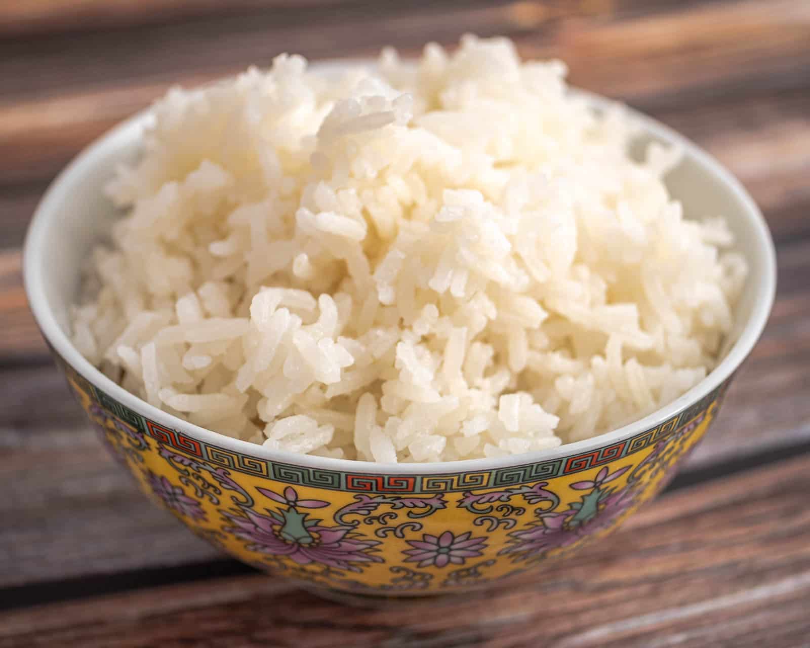 A bowl of white rice on a wood table