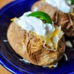 A baked potato loaded with cheese, sour cream, and a jalapeno slice