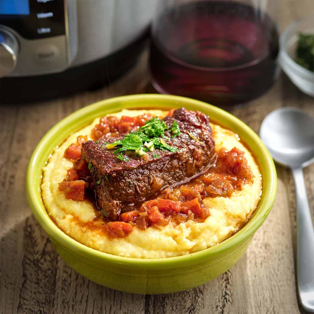 A boneless beef short rib covered in wine sauce on a bed of polenta