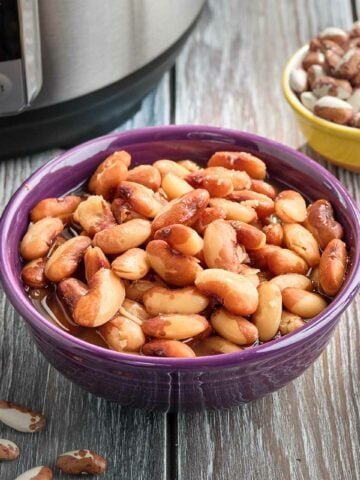 A bowl of cooked snowcap beans with a smaller bowl of uncooked snowcap beans