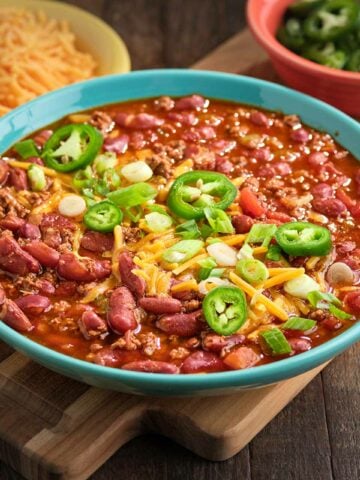A bowl of 5 ingredient chili, topped with cheese, jalapenos, and green onion