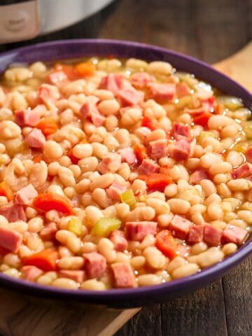 Cooked ham and beans in a purple bowl