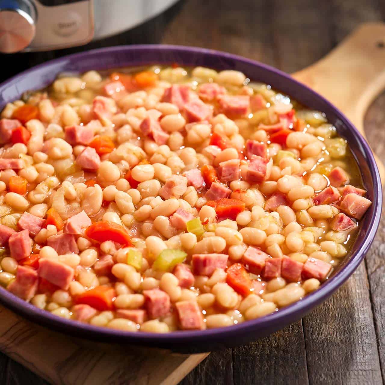 Cooked ham and beans in a purple bowl