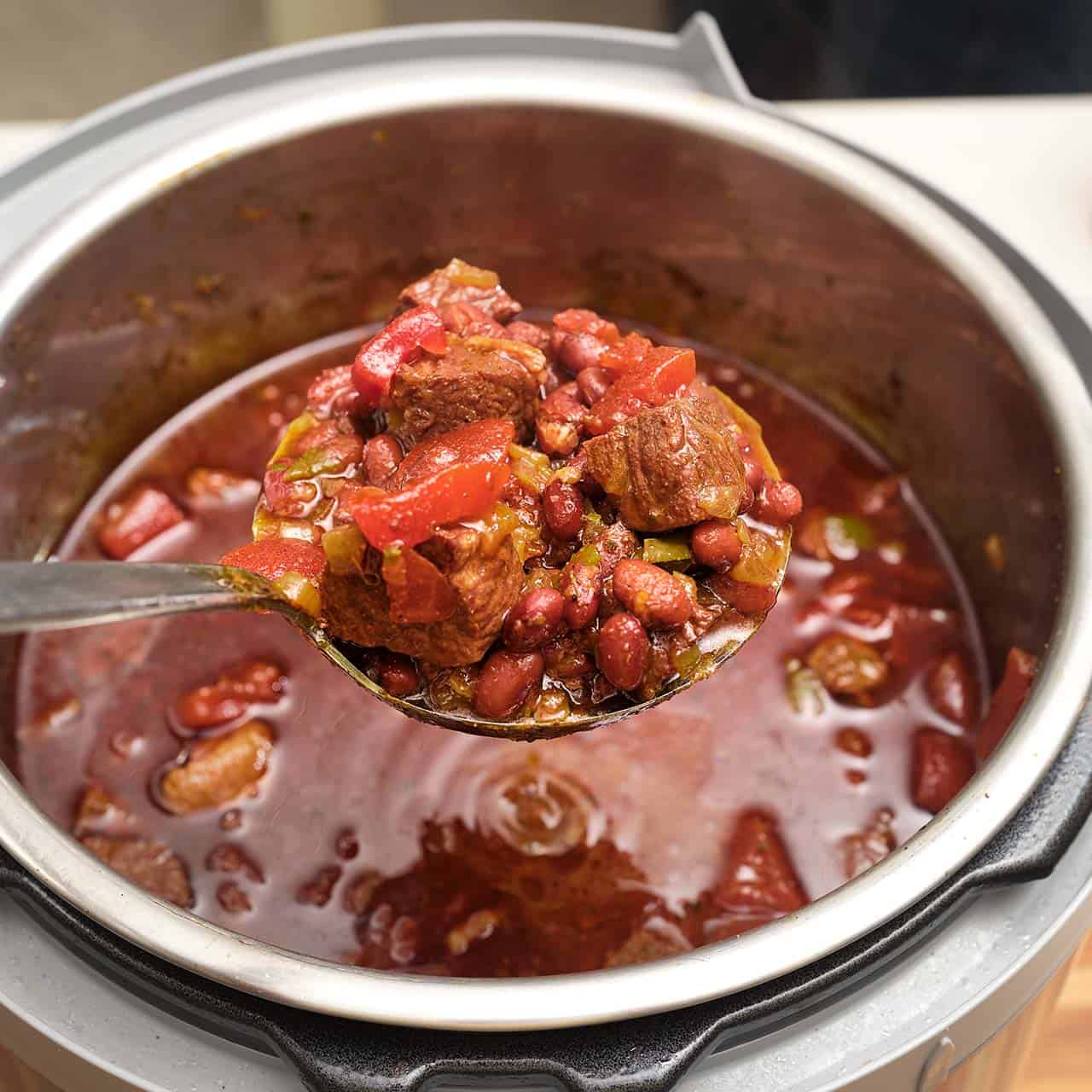 A ladle of chili lifted out of an instant pot