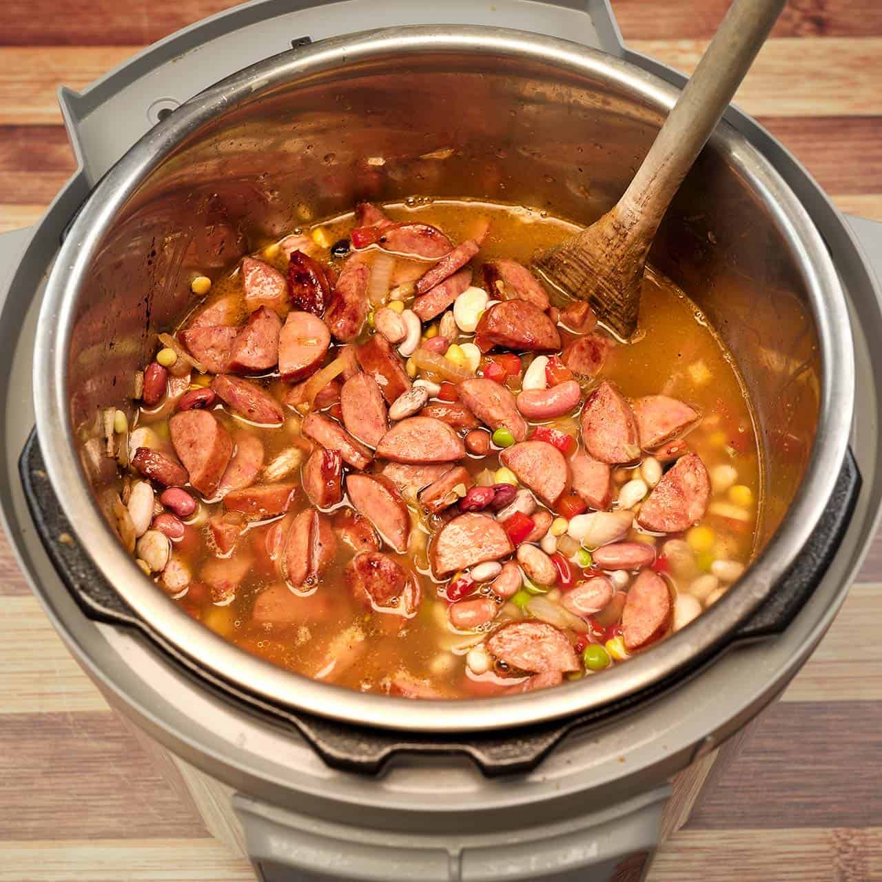 An instant pot full of beans, sausage, and broth, ready to cook