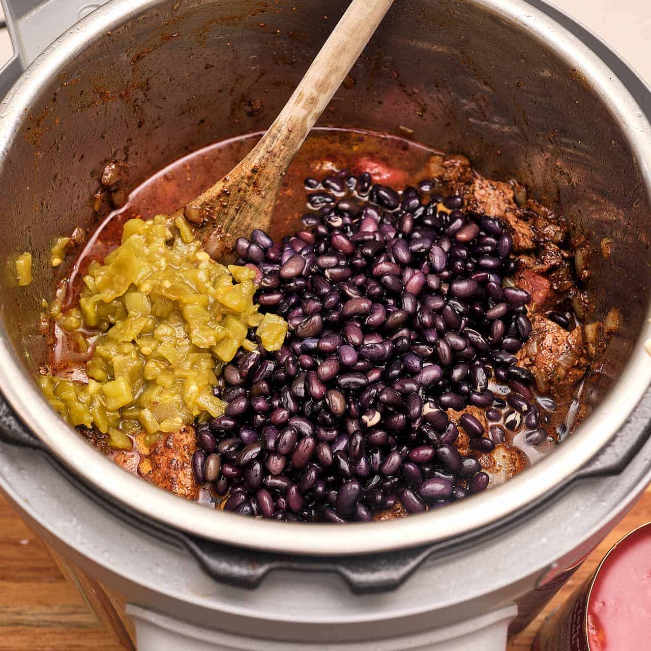 An instant pot full of beef, broth, chiles, and beans