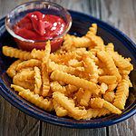 A platter of crinkle cut french fries with a bowl of ketchup