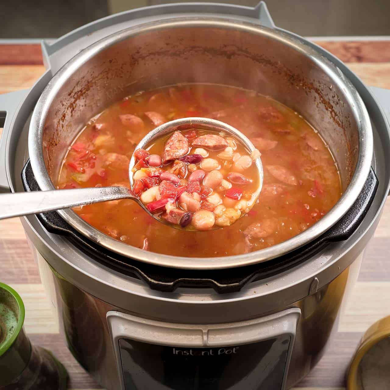 A ladle of 15 bean soup with sausage lifted from an Instant Pot