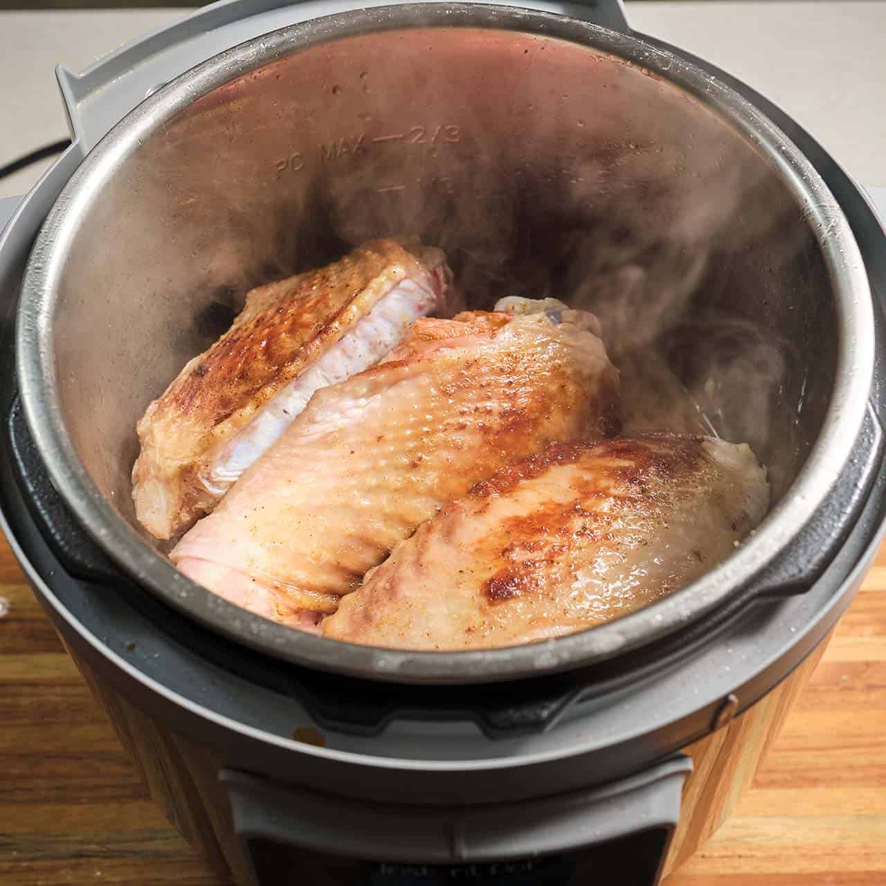 Browned turkey wings stacked in an Instant Pot