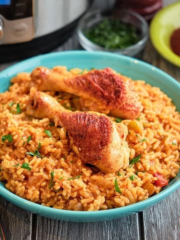 A bowl of chicken legs and rice with an Instant Pot in the background