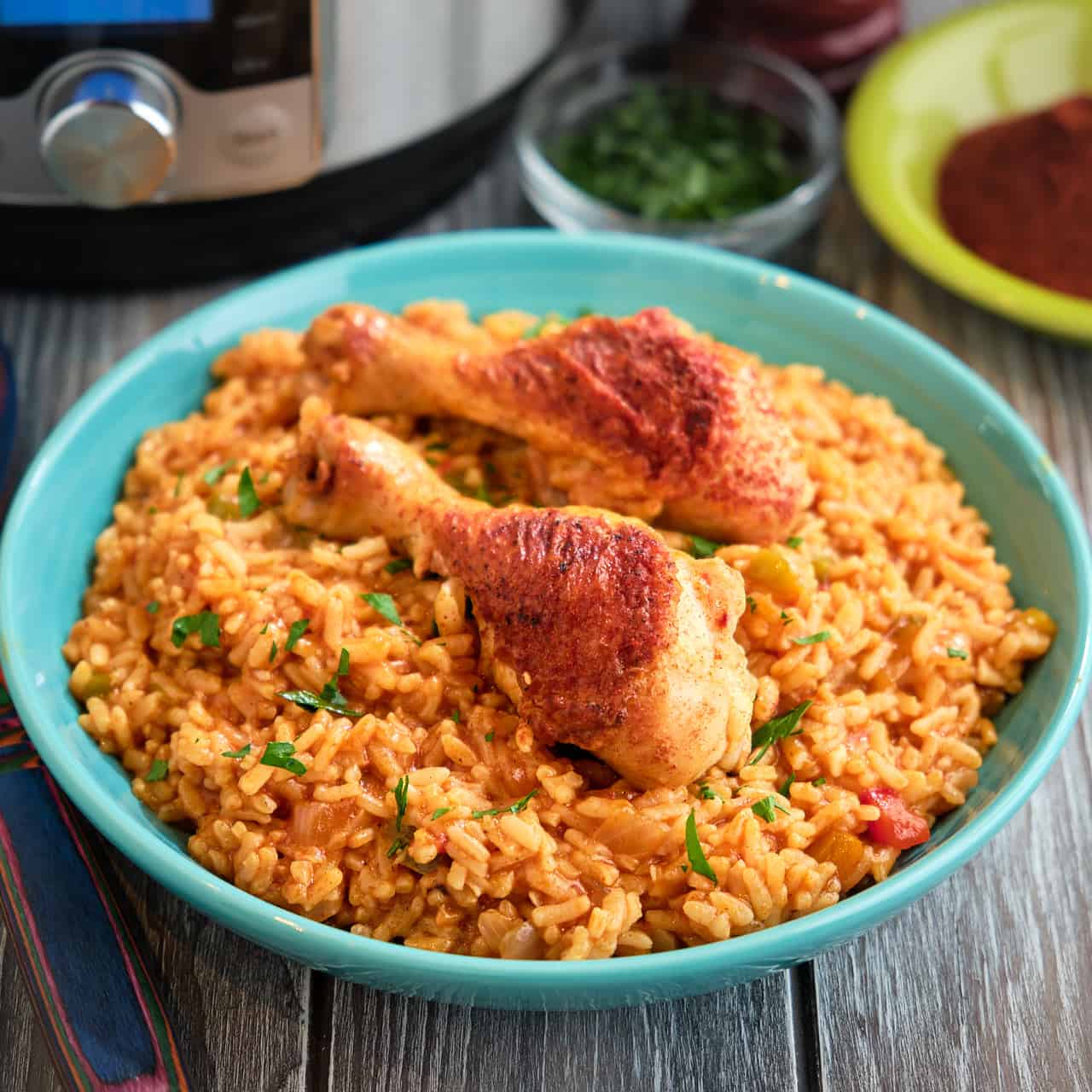 A bowl of chicken legs and rice with an Instant Pot in the background