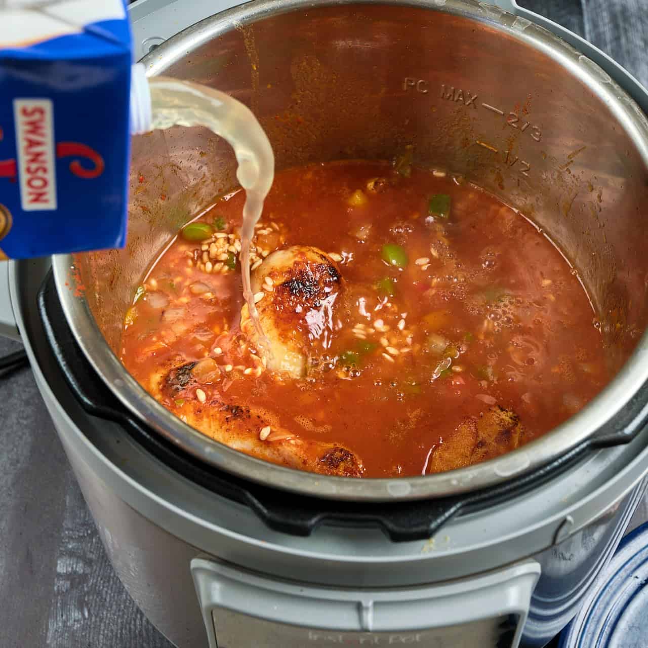 Pouring chicken broth into an Instant Pot with rice and chicken