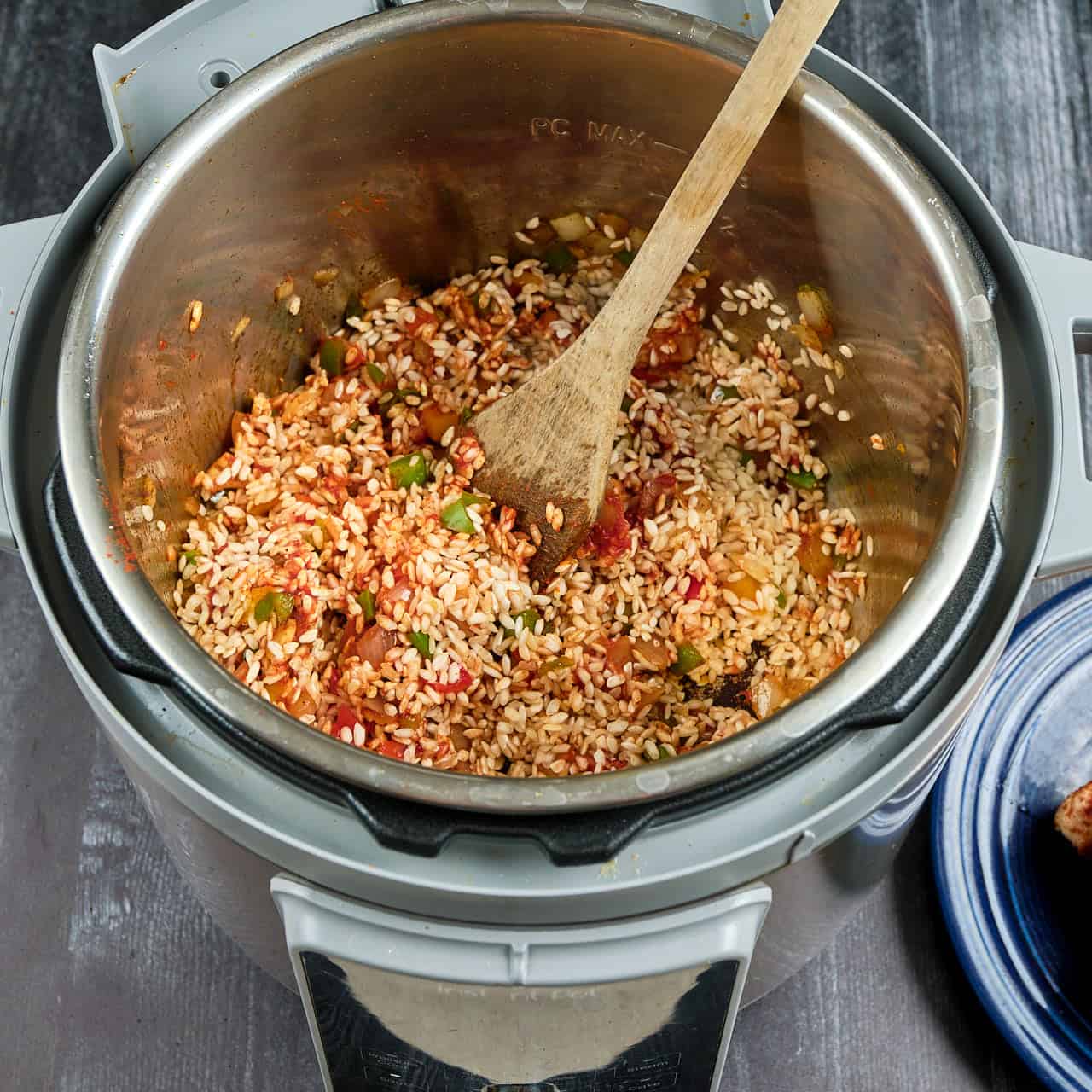 An instant pot with rice stirred into the onions, peppers, and tomato paste