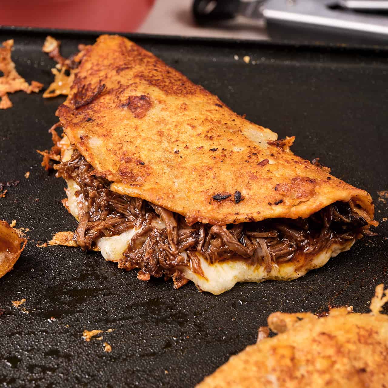 A birria taco cooking on the griddle