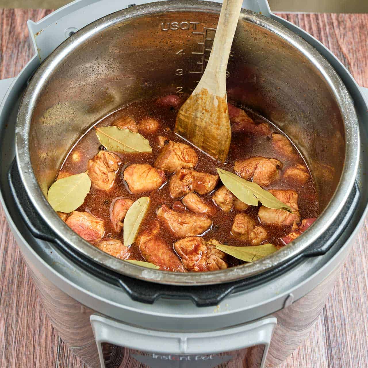 An Instant Pot full of pork, soy sauce, and bay leaves