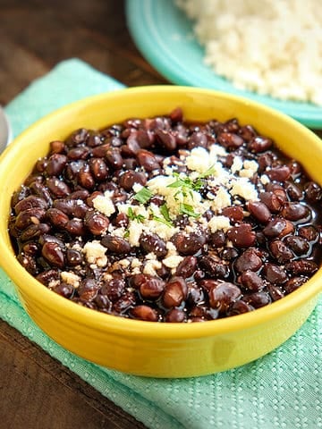 A bowl of Mexican black beans sprinkled with cheese and cilantro