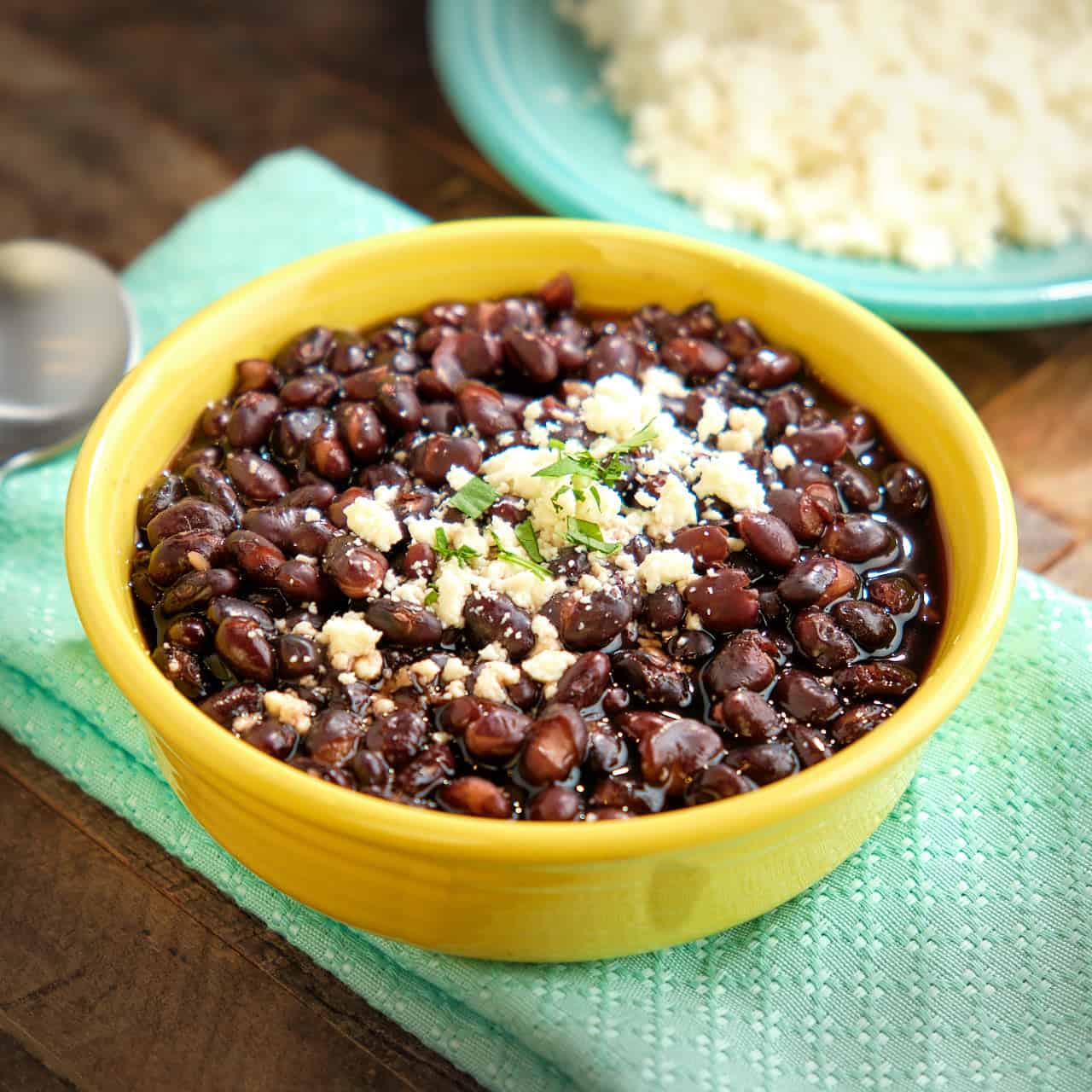 A bowl of Mexican black beans sprinkled with cheese and cilantro