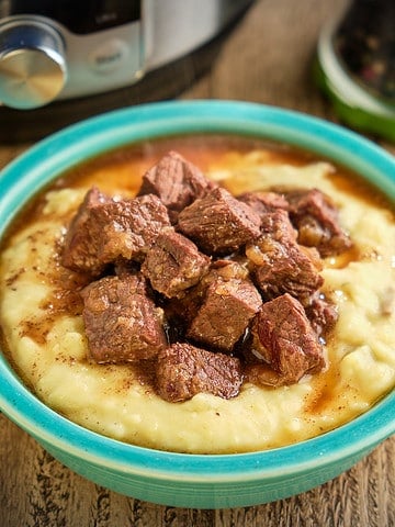 A bowl of beef tips and gravy on mashed potatoes