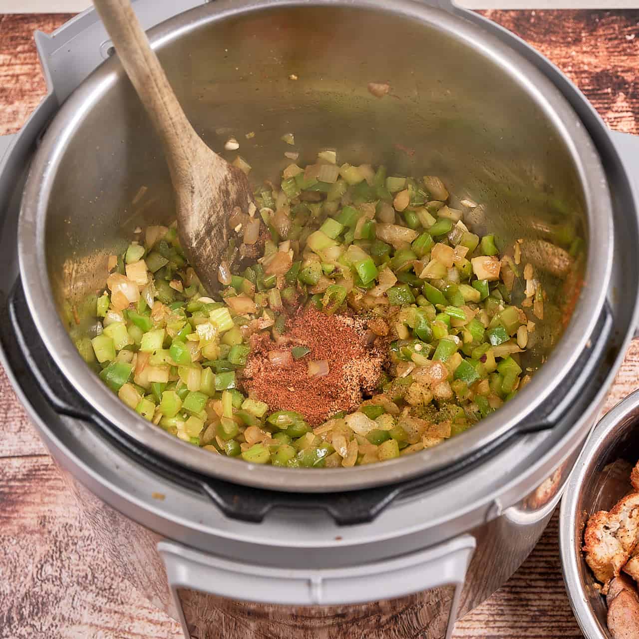 An Instant Pot full of sauteed onions, peppers, and celery, with Cajun Seasoning in the middle.