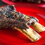 A two-bone slab of beef ribs on a red plate