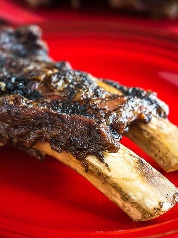A two-bone slab of beef ribs on a red plate