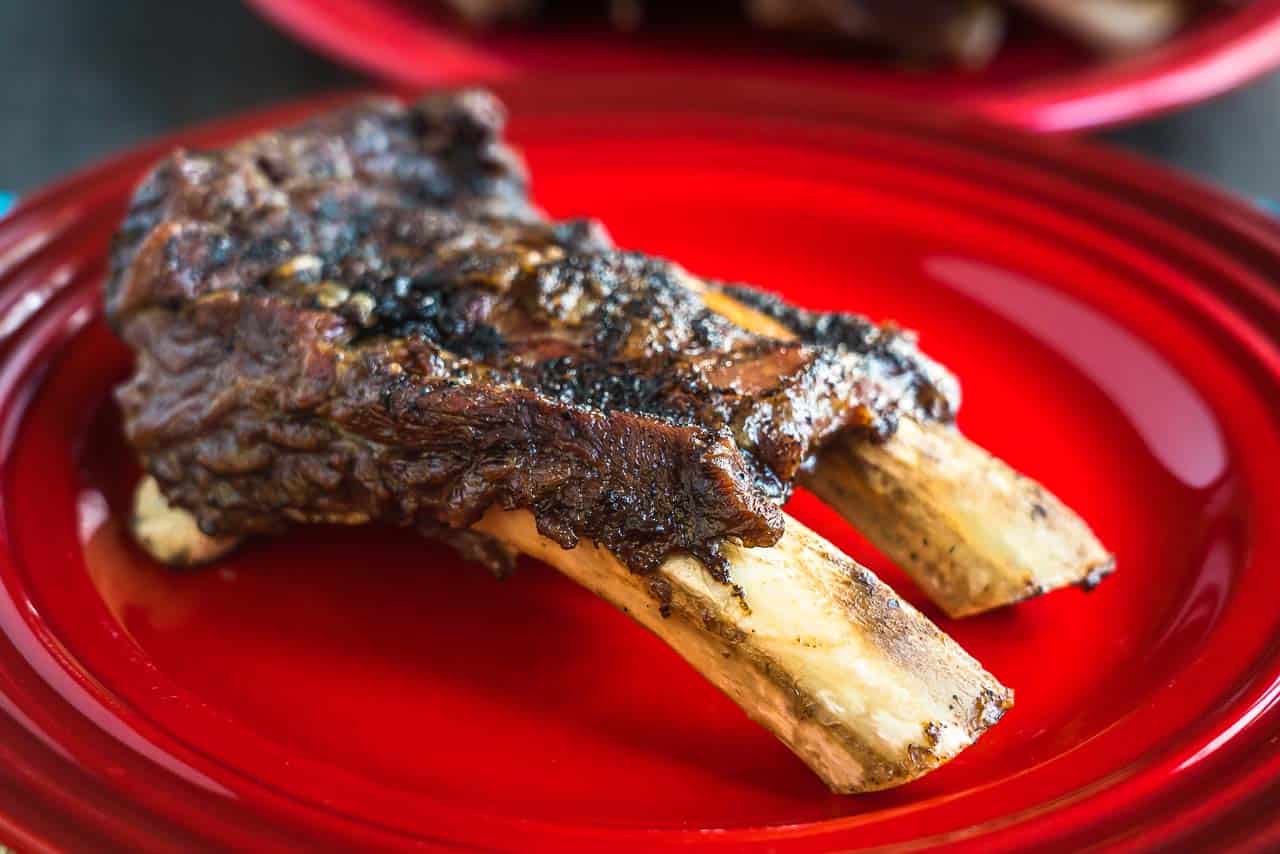 A two-bone slab of beef ribs on a red plate