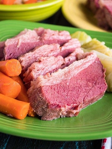 A plate of sliced corned beef with cabbage and carrots
